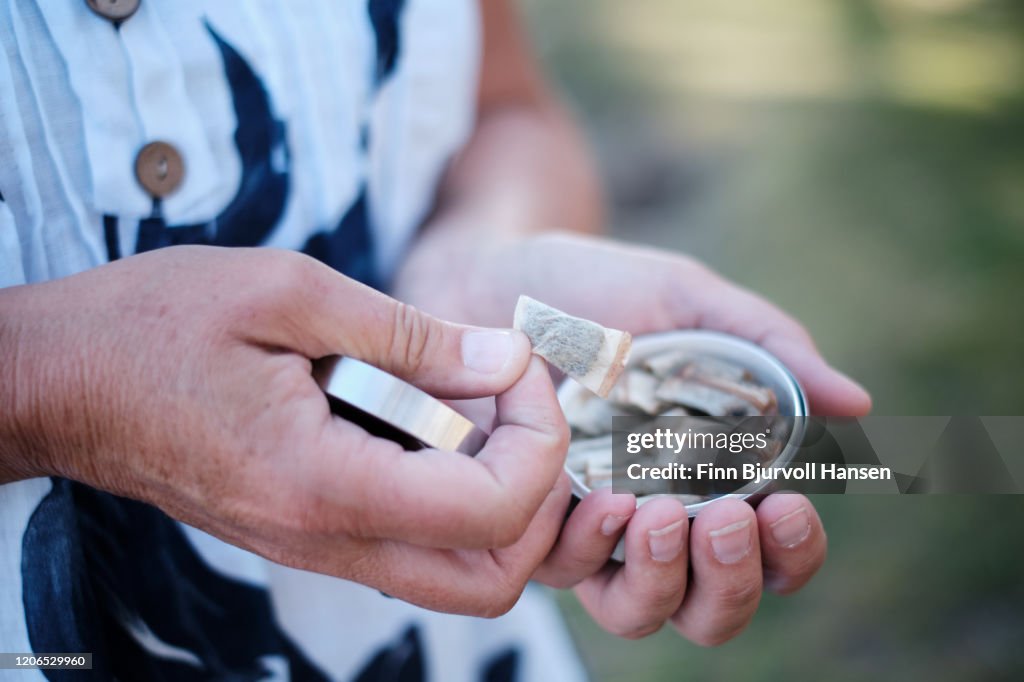 Hands picking up a portion of snus snuff from a box