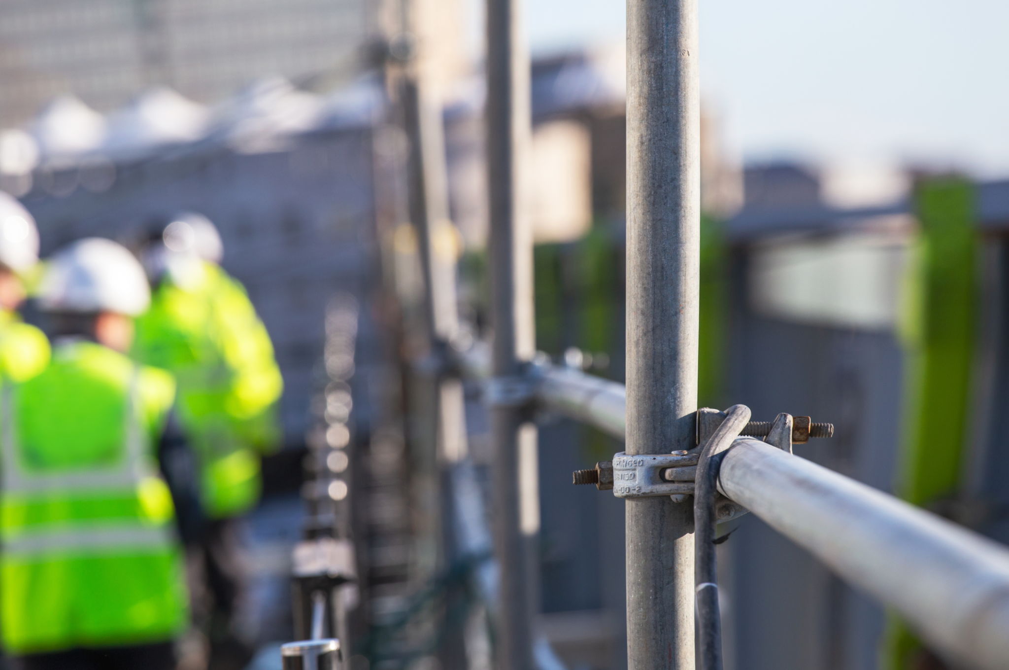 Silhouette Construction workers on a scaffold - Extensive scaffolding providing platforms for work in progress - Men walking on roof surrounded by scaffold - Focus on scaffolding frame - Blue filter Silhouette Construction workers on a scaffold - Extensive scaffolding providing platforms for work in progress - Men walking on roof surrounded by scaffold - Focus on scaffolding frame - Blue filter
