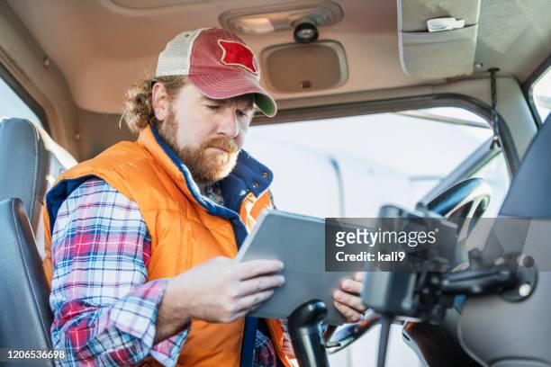 man driving semi-truck using digital tablet - trucker hat stock pictures, royalty-free photos & images