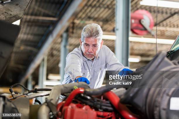 senior hispanic mechaniker reparatur semi-truck - motorhaube stock-fotos und bilder