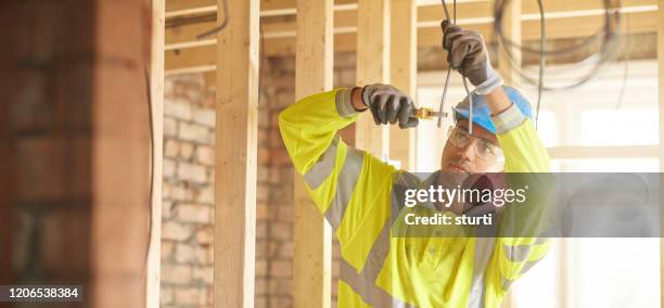 jonge elektricien op bouwplaats - man cutting wire stockfoto's en -beelden