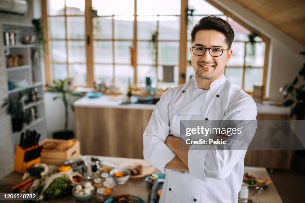 young man in chef's whites posing in his kitchen - personal chef stock pictures, royalty-free photos & images