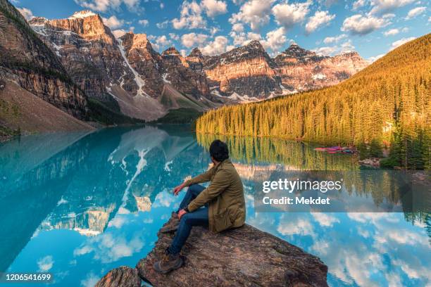 man looking at moraine lake and the clear reflection in summer, one of the most beautiful places in banff national park, alberta, canada - banff stock-fotos und bilder