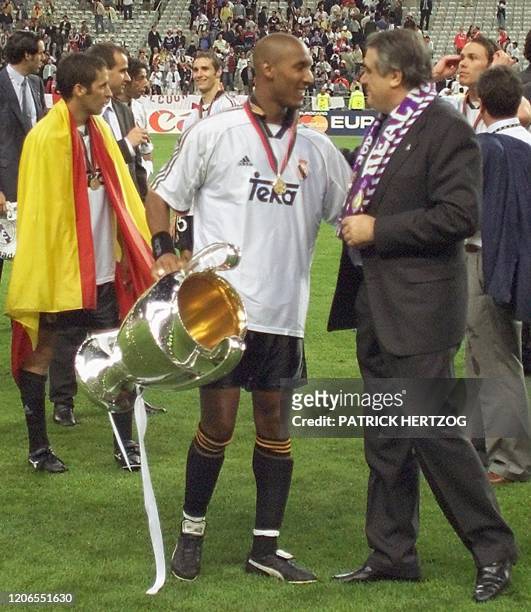 French forward of Real Madrid Nicolas Anelka holding the Champion's League trophy and President Lorenzo Sanz celebrate 24 May 2000, following Real...