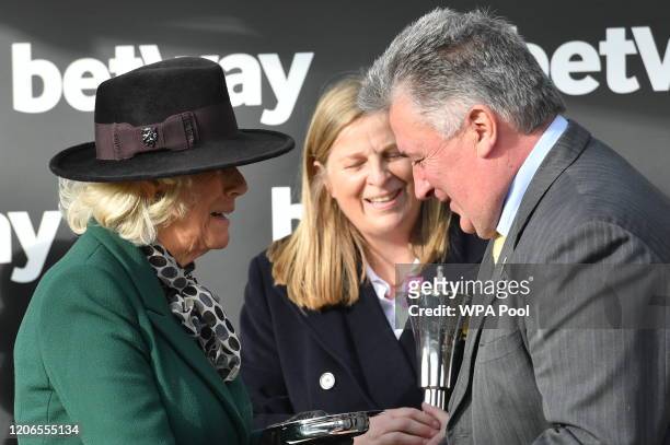 Camilla, Duchess of Cornwall awards the trophy for the Queen Mother Champion Chase to the trainer of Politologue, Paul Nicholls as she attends Ladies...