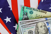 Stimulus economic tax return check and US 100 dollar bills currency with US flag