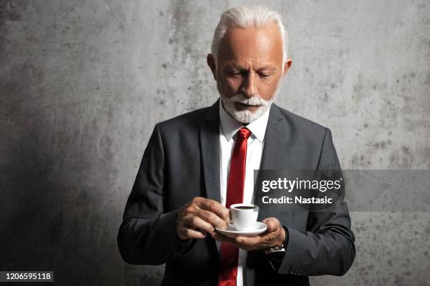 reife geschäftsmann in klassischen anzug trinken kaffee - espresso mann stock-fotos und bilder