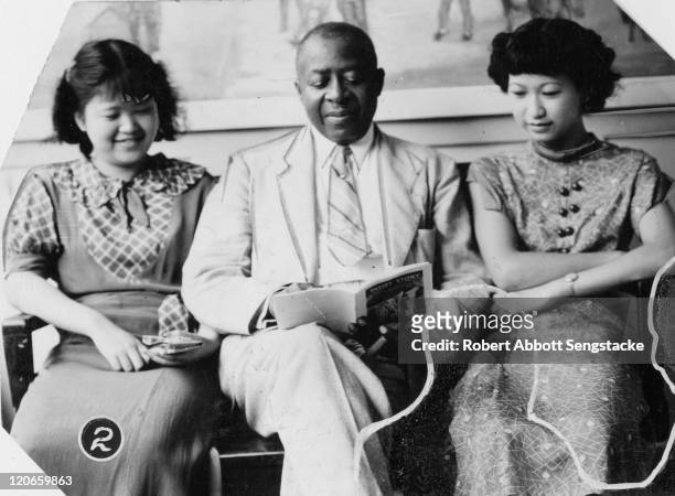American newspaper publisher Robert Sengstacke Abbott reads with two unidentified Chinese students at Chicago Defender building, Chicago, Illinois,...