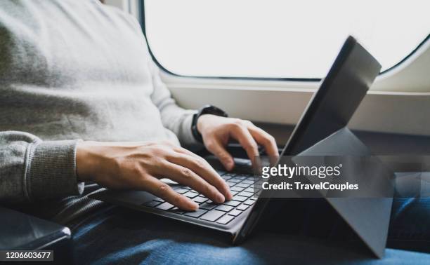 businessman on train working on laptop computer. freelancer men in white sweater working with laptop in the train. business travel or technology concept. - laptop on bus stock-fotos und bilder