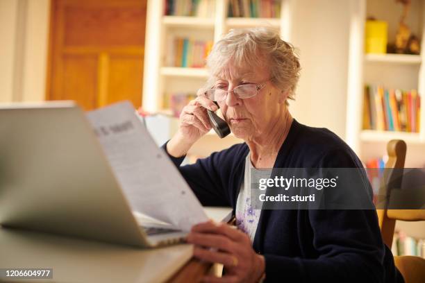 donna anziana interrogando un disegno di legge - customer service documents foto e immagini stock