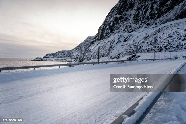 icy road against snowcapped mountain - snow parking lot stock pictures, royalty-free photos & images