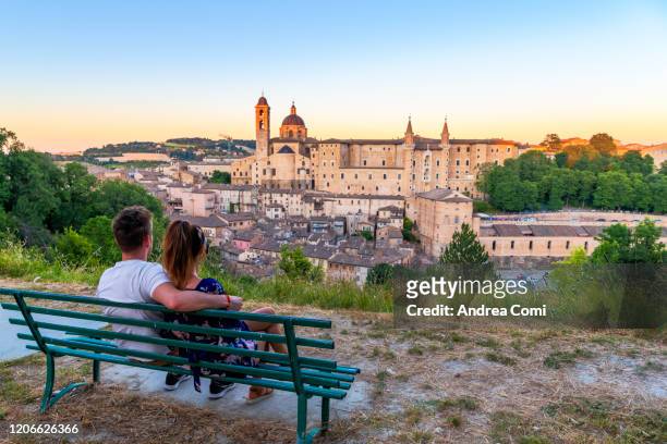 couple of young tourists admiring the view over the historic center of urbino. italy - urbino fotografías e imágenes de stock