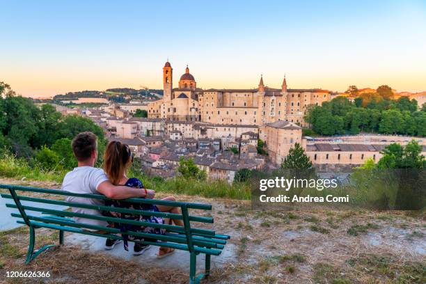 couple of young tourists admiring the view over the historic center of urbino. italy - marche italy stock pictures, royalty-free photos & images