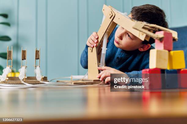 6-7 years old child invented a robotic arm with cardboard and syringe. robotic is his homework. he is a successful student in elementary school. - invented stock pictures, royalty-free photos & images