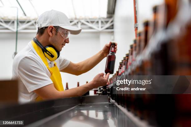 uomo che controlla il funzionamento di una macchina per l'imbottigliamento - bottle beer foto e immagini stock