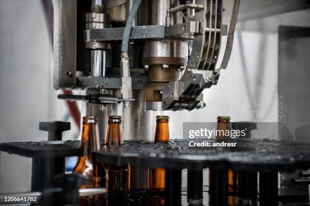 close-up op een bottelmachine die bij een bierfabriek werkt - brouwerij stockfoto's en -beelden
