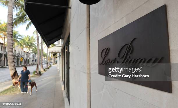 Woman walks two dogs past a Loro Piana store on Worth Avenue as the sun rises on February 14, 2020 in Palm, Beach, Florida.