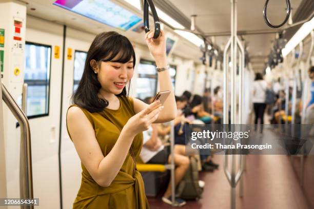 beautiful young lady text messaging on smartphone while riding on subway mtr train - train interior stock pictures, royalty-free photos & images