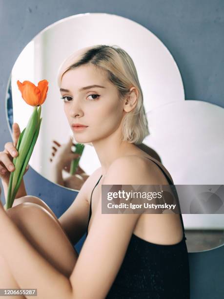 young woman holding red tulip against mirror - studio shot lonely woman stock pictures, royalty-free photos & images