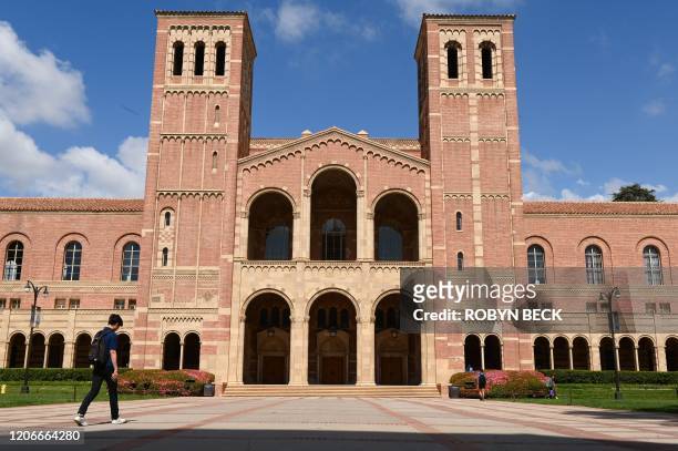 Student walks toward Royce Hall on the campus of University of California at Los Angeles in Los Angeles, California on March 11, 2020. - Starting...