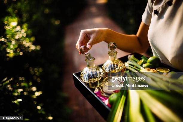 high angle close up of woman holding tray with glass bottles, candles and fruit. - perfume atomizer stock pictures, royalty-free photos & images
