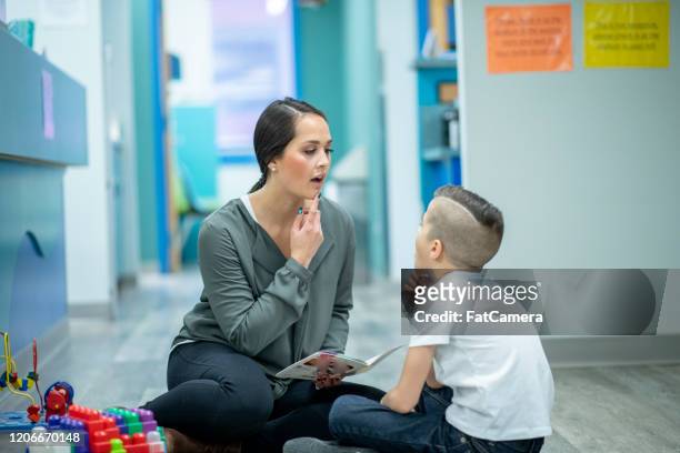 speech therapist sitting with a child stock photo - speech stock pictures, royalty-free photos & images