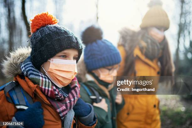 drei kinder mit anti-virus-masken gehen zur schule - coronavirus winter stock-fotos und bilder