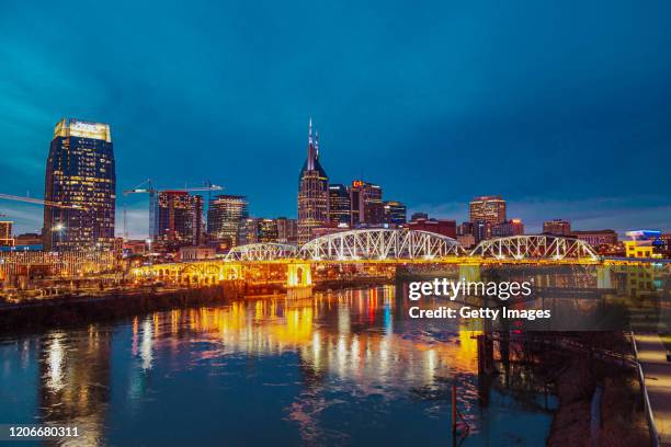 cityscape of nashville at dusk on the cumberland river. shown is the john seigenthaler pedestrian bridge. outdoor shots of city scenes in nashville, tennessee during winter. - nashville winter stock pictures, royalty-free photos & images
