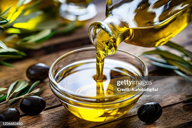 gieten van extra vergine olijfolie in een glazen kom - olijfolie stockfoto's en -beelden