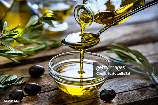 gieten van extra vergine olijfolie in een glazen kom - olive fruit stockfoto's en -beelden