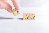 3 Star Ranking Formed By Wooden Blocks And Arranged By A Male Finger On A White Table