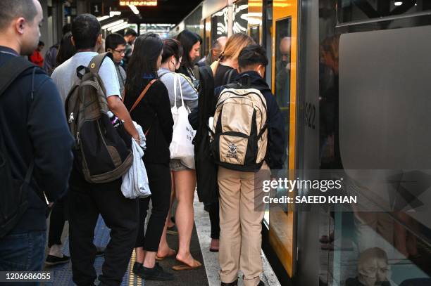 Passengers queue up to ride on a city train In Sydney on March 12, 2020. - Australia is to unveil a massive 11 billion USD spending plan designed to...