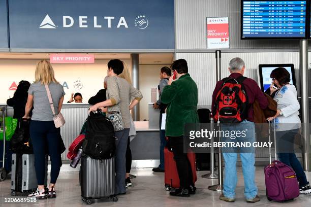 Travellers queue at a Delta Airlines desk at Paris-Charles-de-Gaulle airport after a US 30-day ban on travel from Europe due to the COVID-19 spread...