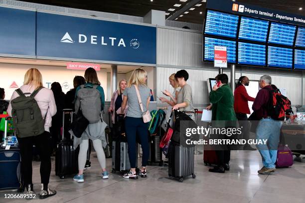 Travellers queue at a Delta Airlines desk at Paris-Charles-de-Gaulle airport after a US 30-day ban on travel from Europe due to the COVID-19 spread...