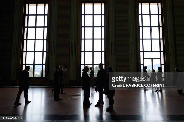 Delegates of the United Nations Human Rights Council are seen in silhouette outside of the assembly hall during a session in Geneva on March 12,...
