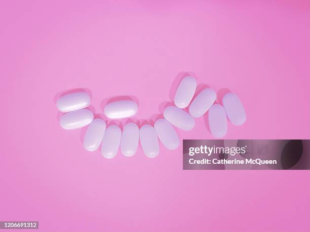 white medicine pills on pink background - cholesterol medication stock pictures, royalty-free photos & images