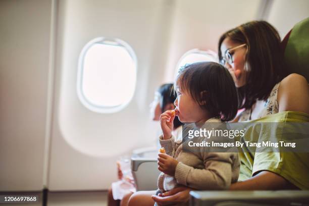 little girls travelling joyfully with mom on airplane - mother and child snacking stockfoto's en -beelden
