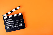 Movie clapper board on orange background with copy space.