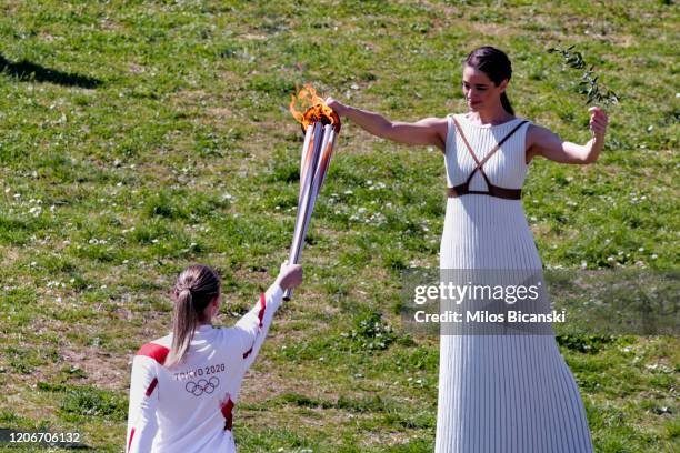 Greek actress Xanthi Georgiou, playing the role of High Priestess passes the flame to the first torchbearer, Greek shooting athlete Anna Korakaki,...