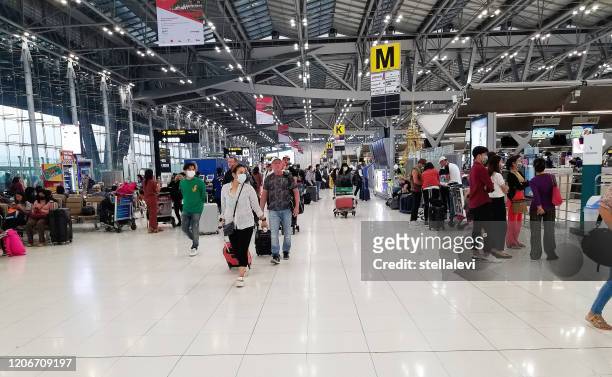 travelers with luggage at the airport in bangkok wearing masks for protection against the coronavirus - thailand covid stock pictures, royalty-free photos & images