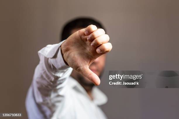 man showing thumbs down sign , giving thumb down as sign of failure on gray background. customers feedback concept - bad luck 個照片及圖片檔