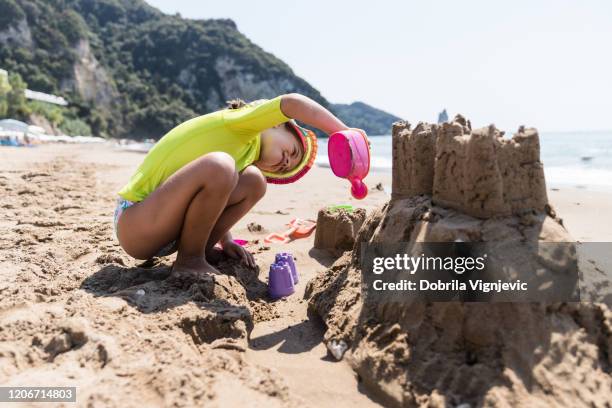 mädchen mit spielzeug, um eine sandburg zu machen - sandkasten stock-fotos und bilder