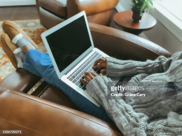 woman works on laptop while reclining in chair - parte del cuerpo humano fotografías e imágenes de stock