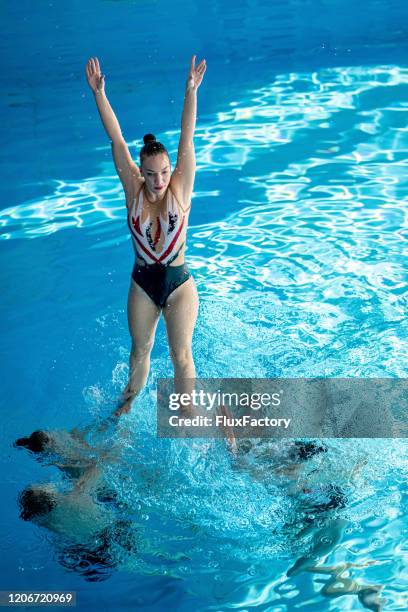 femme sautant hors de l’eau pendant une chorégraphie synchronisée de natation - synchronized swimming photos et images de collection