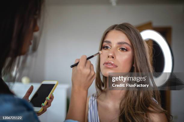 beautician putting makeup on her client - bronze mirror stock pictures, royalty-free photos & images