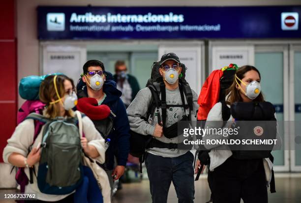 Passengers wearing face masks as a preventive measure against the spread of the COVID-19 coronavirus arrive at Ezeiza International Airport in Buenos...