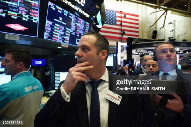 Floor Governor looks on as traders work on the floor at the opening bell of the Dow Industrial Average at the New York Stock Exchange on March 12,...