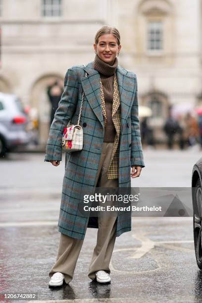 Emili Sindlev wears a green checked long coat, a floral print Chanel bag, a brown wool turtleneck pullover, beige flowing pants, white shoes, during...
