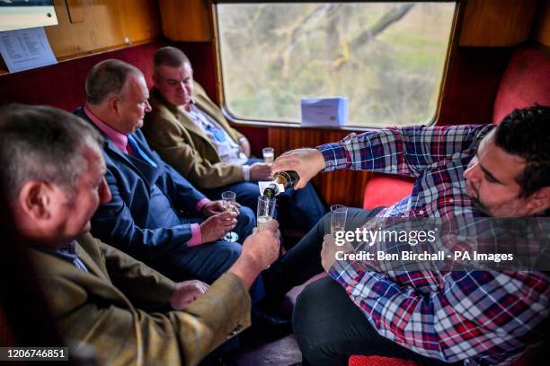 Racegoers pour Champagne aboard a vintage train carriage at Toddington station, Gloucestershire, where people are catching a steam train service to...