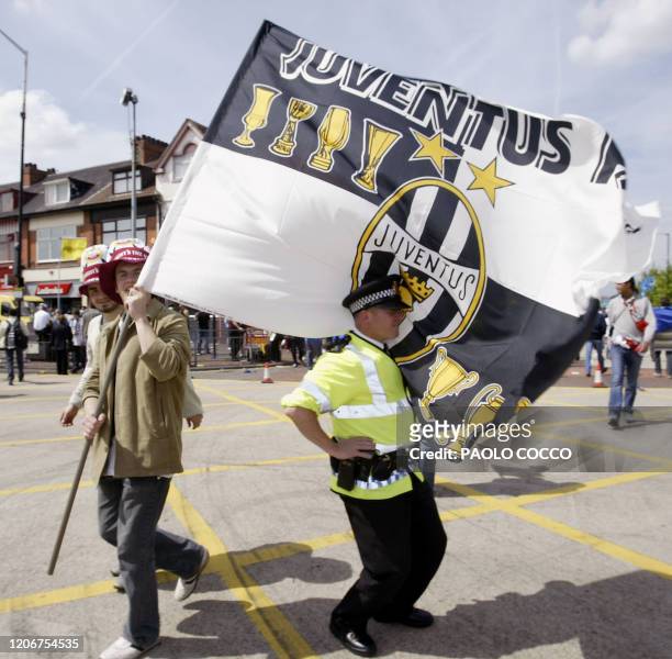 Juventus supporters walks with his soccer team flag next to a policeman near Old Trafford 's Stadium before the European Champions League Final match...